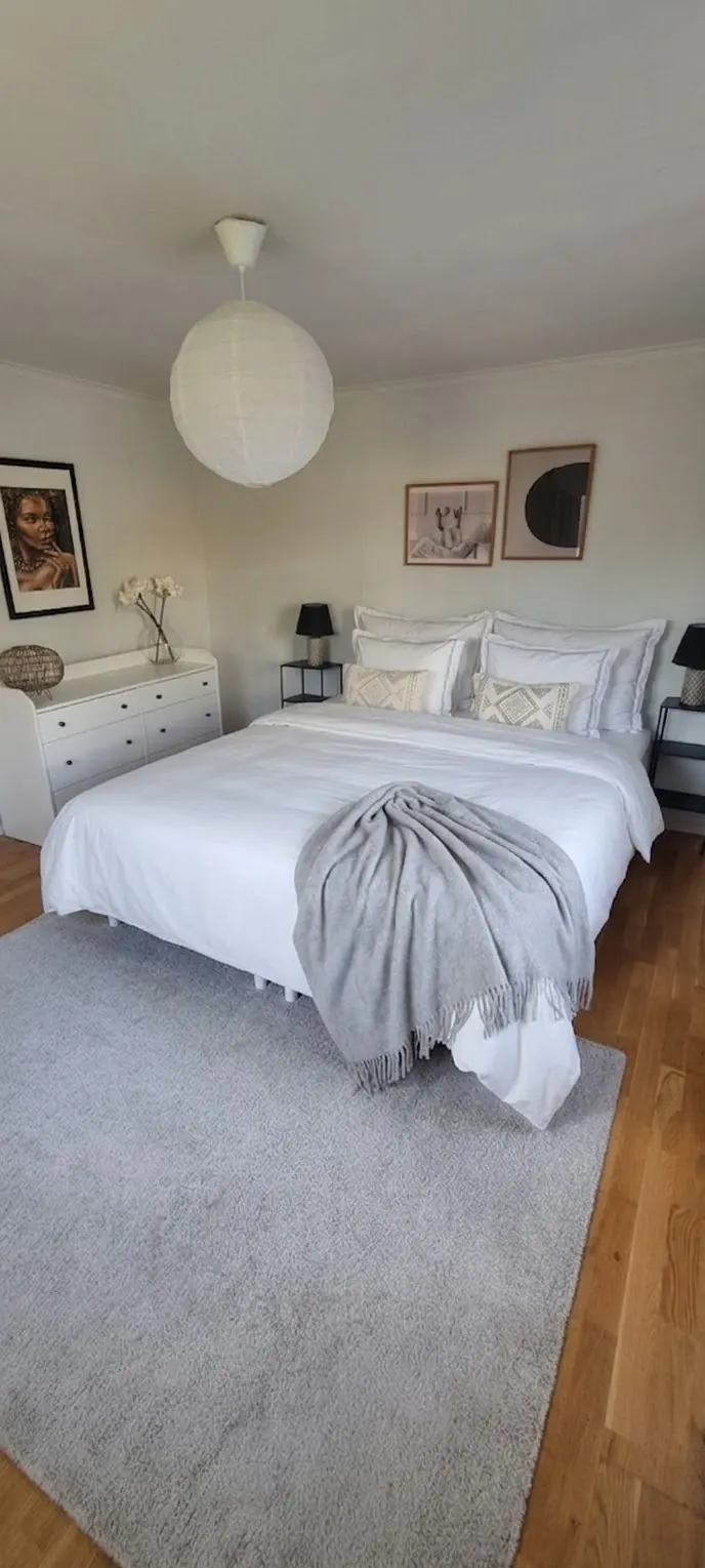 Bedroom with a white double bed, paper lamp and grey rug