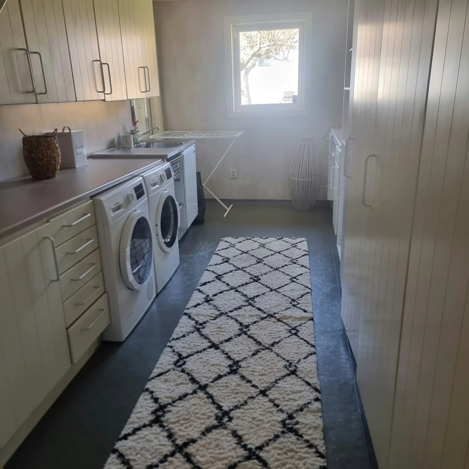 Laundry room with washing machine, tumble dryer, utility sink and drying rack