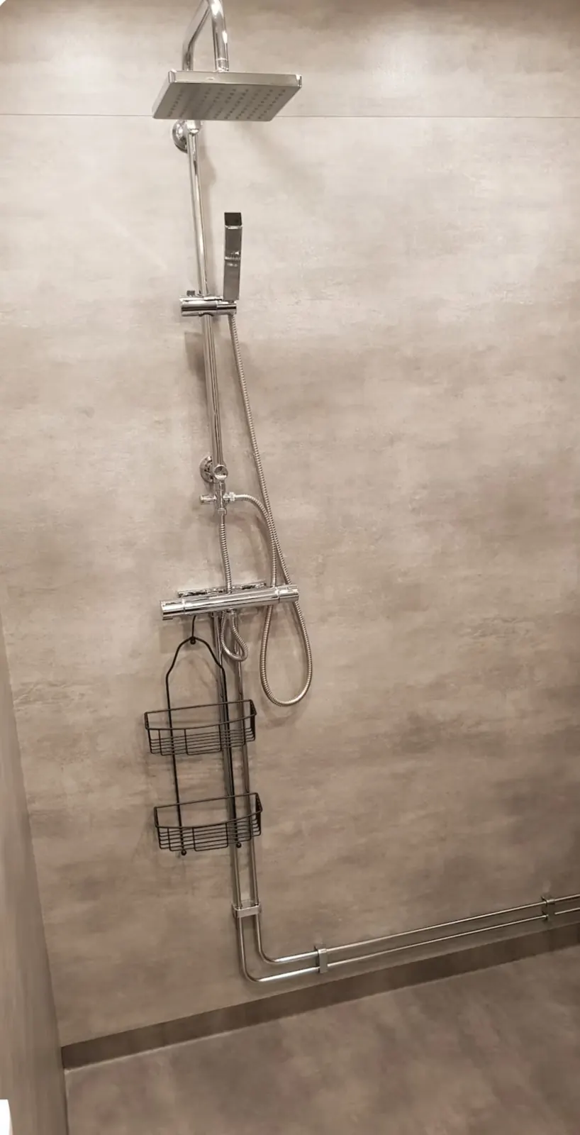 Shower with rain shower and hand shower against a concrete-grey wall