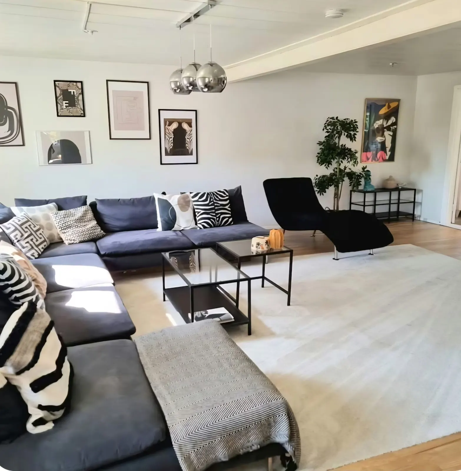 Large living room with a blue corner sofa, glass table and gallery wall